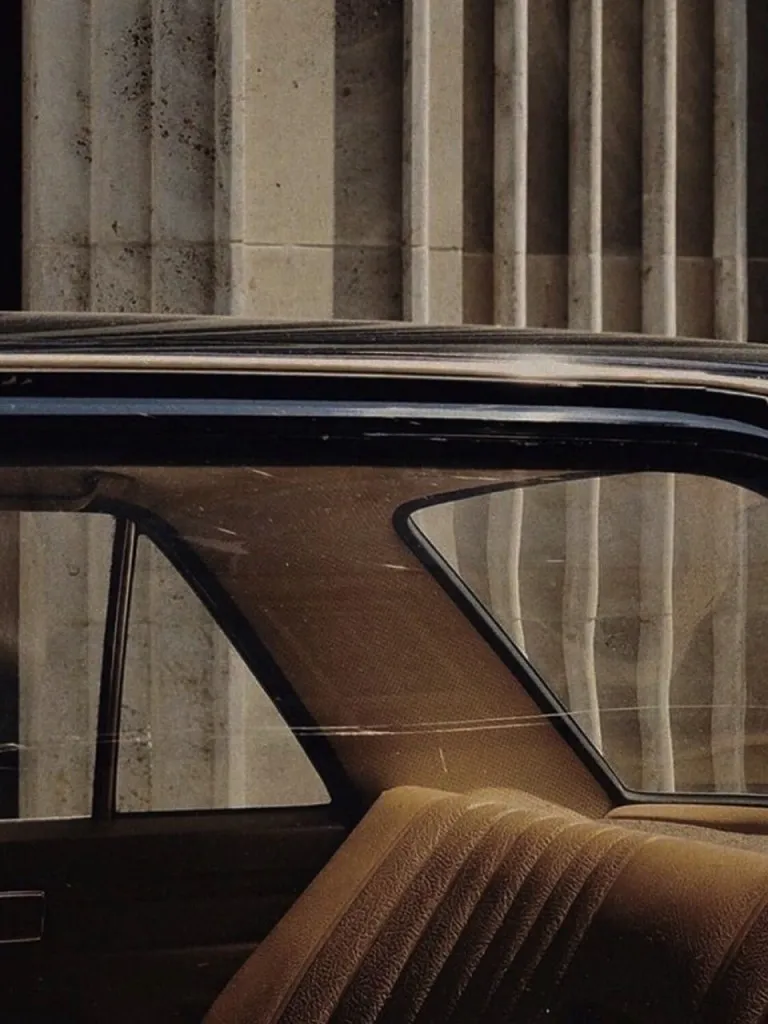 Detail of a vintage car parked in front of a stone façade